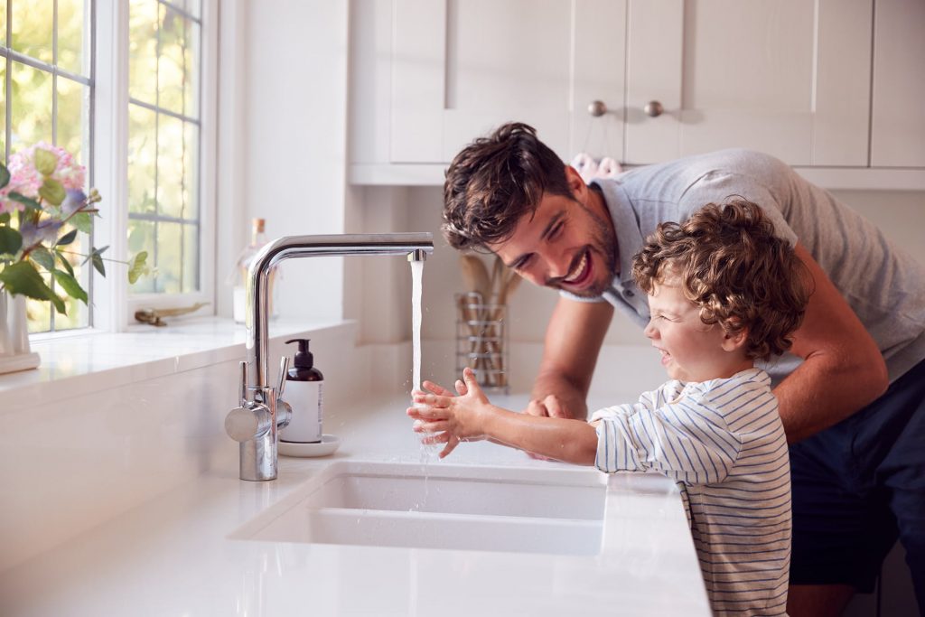 father and son washing their hands together in kitchen sink