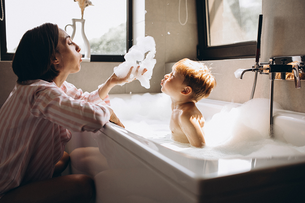 Mother and child, in bathtub, blowing bubbles