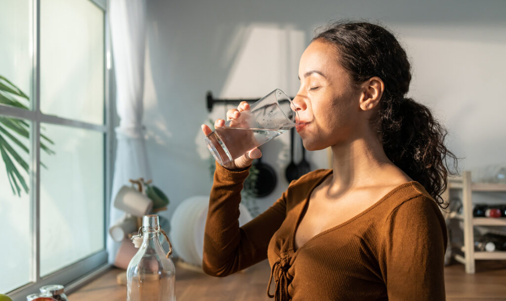 woman drinking water near a window